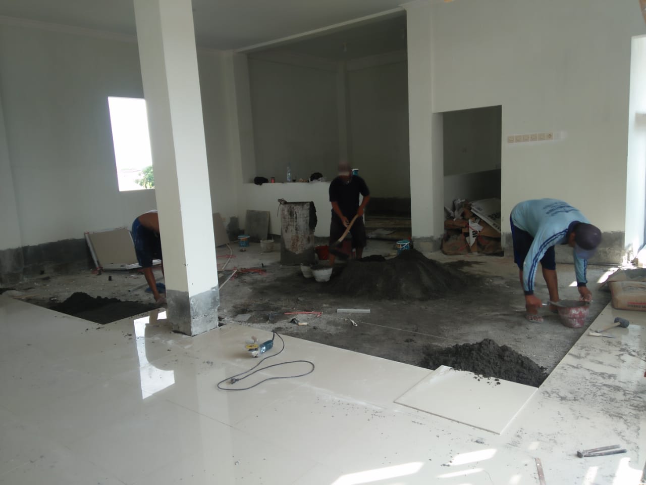 Tiga orang pekerja menyelesaikan pemasangan granit di lantai tiga gedung terpadu PCNU