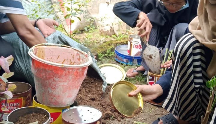 Anggota IPNU-IPPNU Ranting Babadan sibuk menyemai berbagai tanaman obat di kaleng-kaleng bekas