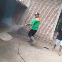 Seorang warga Desa Kapuran mendampingi relawan LPBINU Ponorogo menyemprotkan disinfektan di teras rumahnya