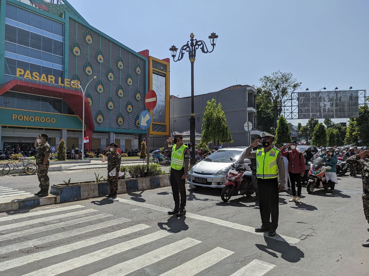 2 Polisi bersama Banser memberi penghormatan kepada bendera merah putih diikuti para pengguna jalan