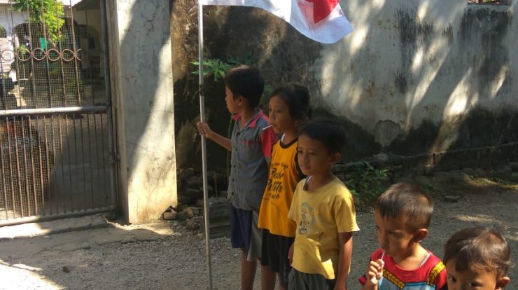 Anak-anak berbaris sebelum menancapkan tiang bendera merah putih di tatakanya