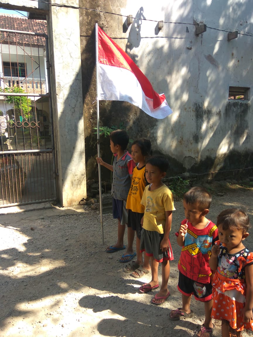 Anak-anak berbaris sebelum menancapkan tiang bendera merah putih di tatakanya